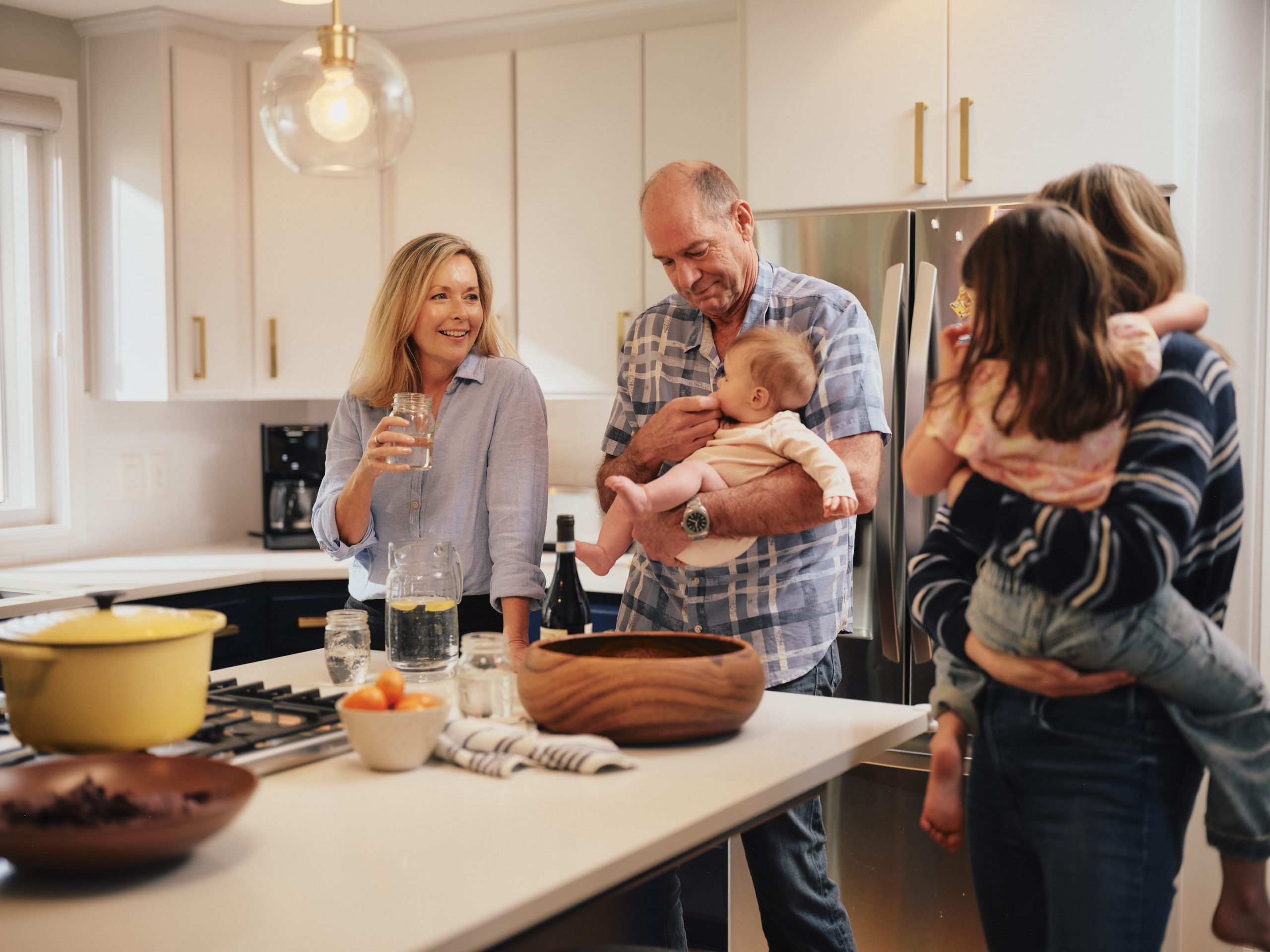 Grandparents and parents gathered in a bright kitchen with a baby