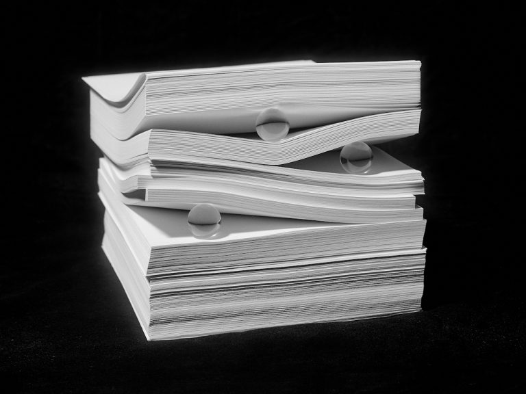 Stacks of white paper with water droplets on a black background