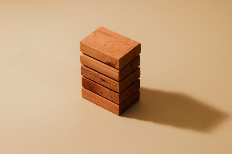 A neat stack of five wooden blocks on a tan background